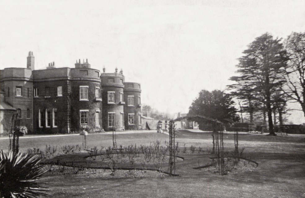 A black and white photo of a house with a fence and trees Description automatically generated with low confidence