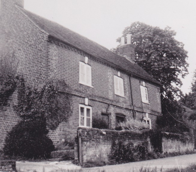 A black and white photo of a house with trees and bushes Description automatically generated with low confidence