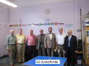 A group of people standing in front of a sign Description automatically generated with medium confidence