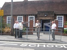 A group of people standing on a sidewalk in front of a brick building Description automatically generated with low confidence