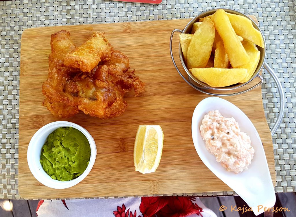 Fish & Chips på en träbricka med grön ärtpure som tillbehör