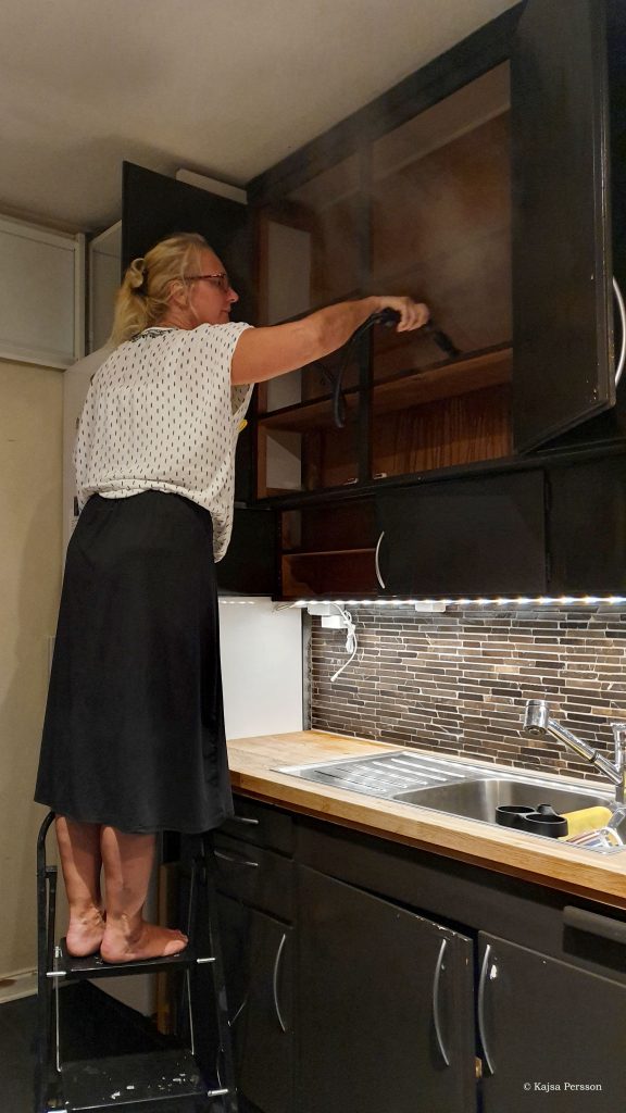 Tjej Ångtvättar köksskåp för att få bort ohyra i köket