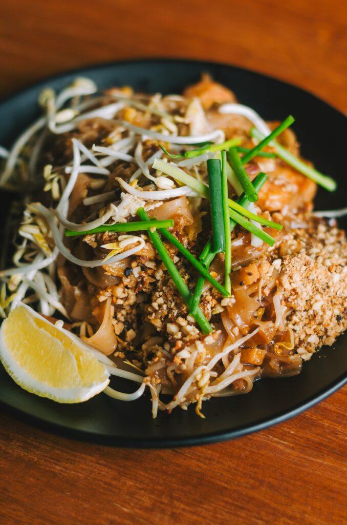 pad thai med citronklyfta på svart tallrik