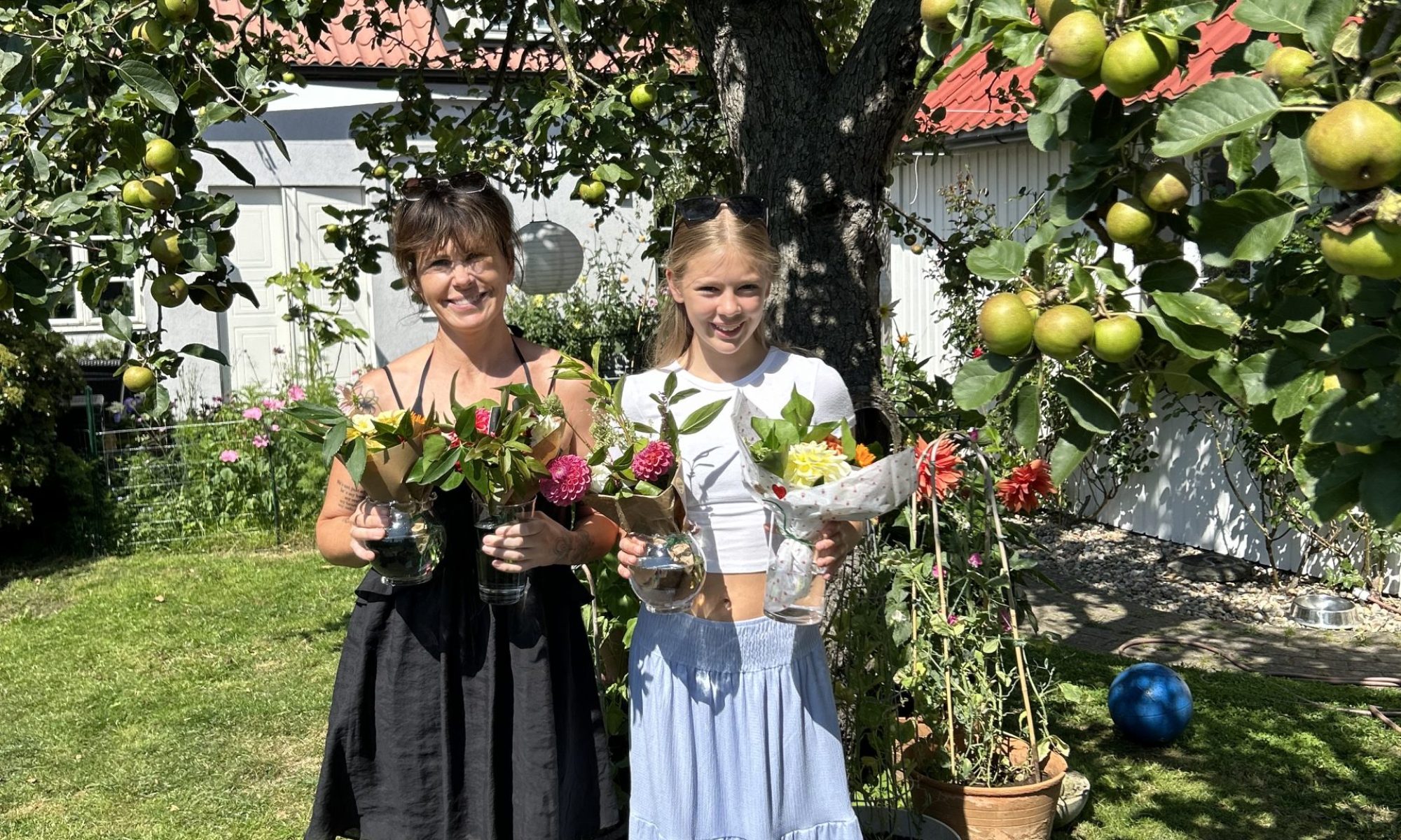 Saga Och Tilde står under ett träd med nybundna blommor I händerna