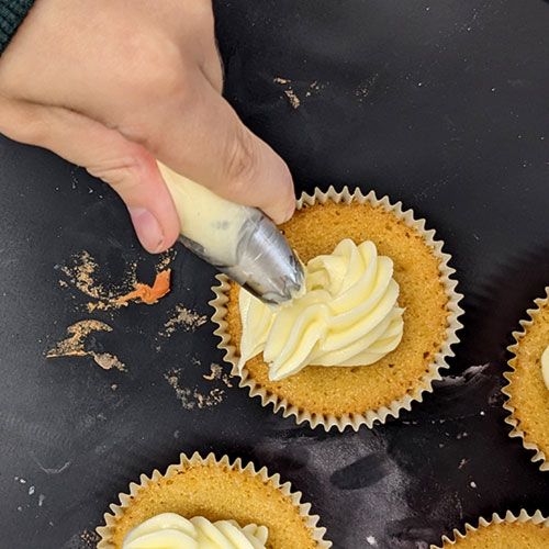 Icing is piped on to a freshly baked cupcake