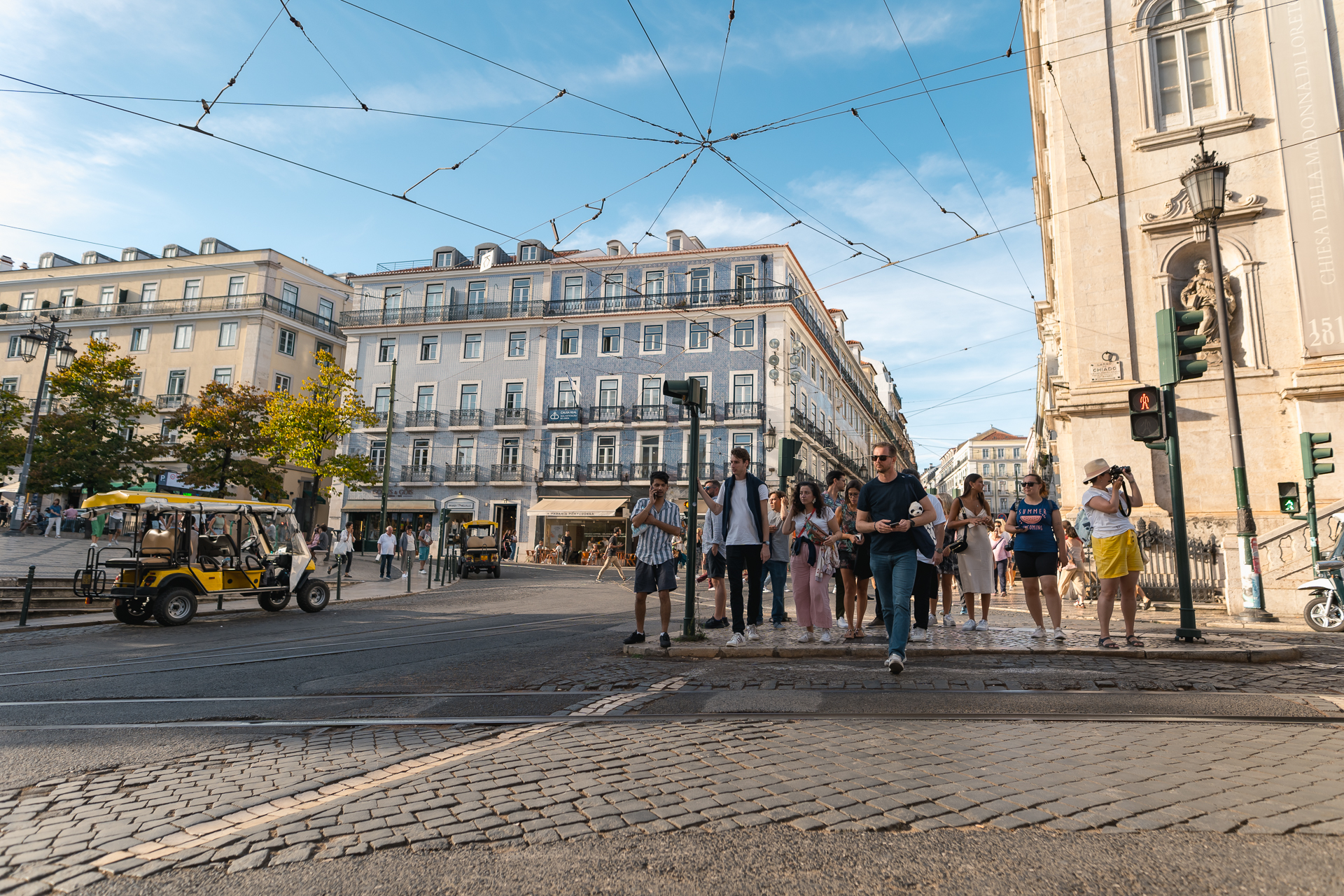 Bustling street scene in the Chiado district of Lisbon with pedestrians, trams, and historic architecture