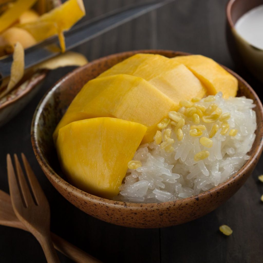 En utsökt portion av mango sticky rice är färdig för servering En thailändsk mango sticky rice ser väldigt god ut och serveras på bambublad.