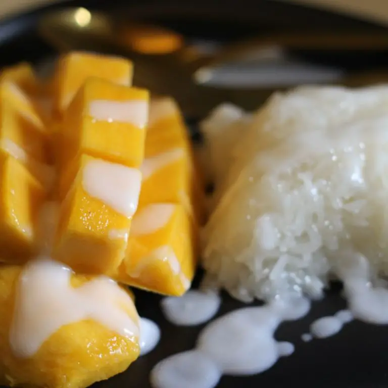 Närbild på saftig mango sticky rice med söt sås över.