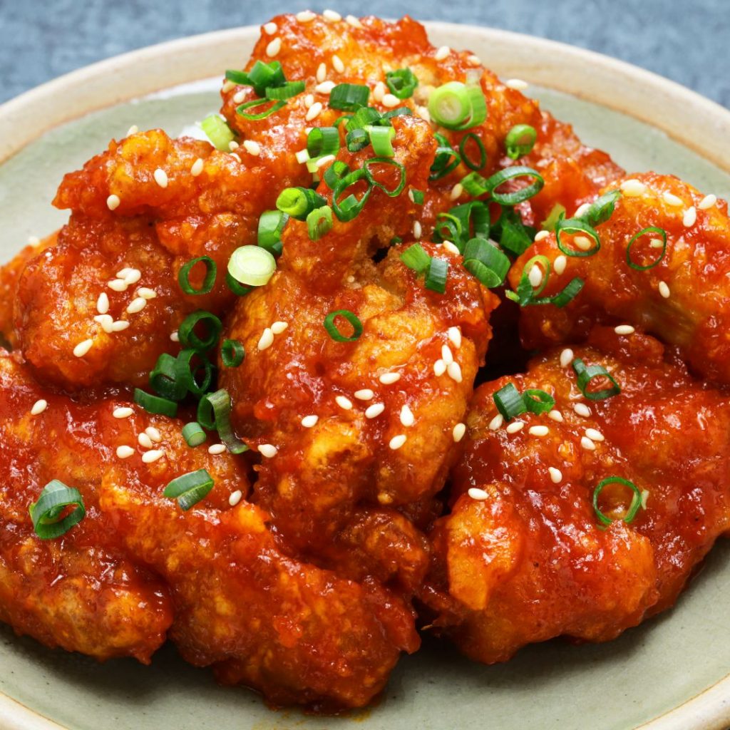 Bild på en tallrik med Yangnyeom Chicken, koreansk friterad kyckling täckt i en röd, klibbig sås
