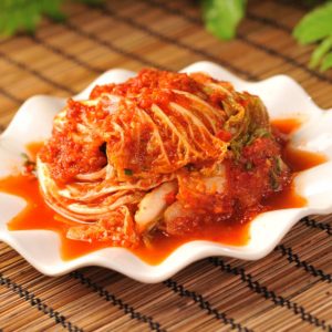 Bild på en liten skål med kimchi, fermenterad kinakål med en röd och kryddig marinad som ger en stark och syrlig smak