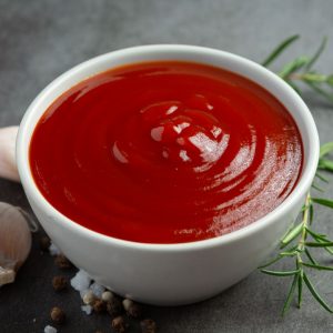 Bild på en skål med ketchup, röd och tjock, med en söt och syrlig smak som används som smaksättare och topping på många maträtter. Bild på en skål med ketchup, röd och tjock, med en söt och syrlig smak som används som smaksättare och topping på många maträtter.