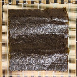 Bild på en stor bit nori, mörkgrön och tunn, med en lätt krispig textur och en mild smak av hav, vanligt i sushi och kimbap.