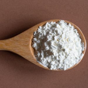 Bild på en träsked med majstärkelse, vitt och silkeslent pulver, för att ge krispighet när det används i friterade rätter. Bild på en träsked med majstärkelse, vitt och silkeslent pulver, för att ge krispighet när det används i friterade rätter.