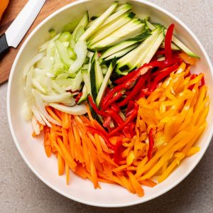 Bild på färgglada julienne-skurna grönsaker, som morötter, paprika och zucchini.