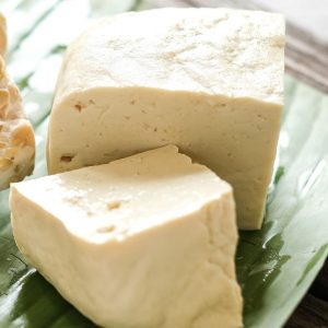 Block av tofu, vit och fast, redo att skivas och användas i både sallader och varma rätter.