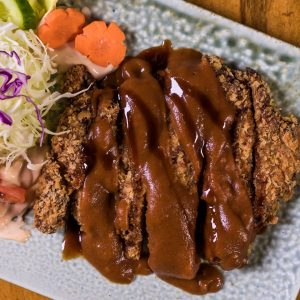Brun krämig tonkatsusås över en tonkatsu, söt, umamirik och glansig för extra smak.