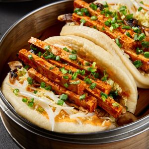 En bao bun fylld med marinerad tofu och fräscha grönsaker, ett vegetariskt alternativ med färgglada ingredienser.