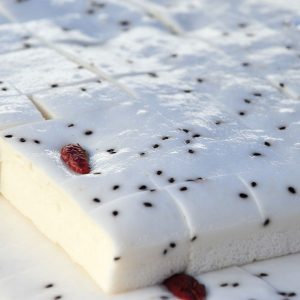 En bild på Baekseolgi, en koreansk vit ångad riskaka, lätt och fluffig garnerad med sesamfrön och jujubär
