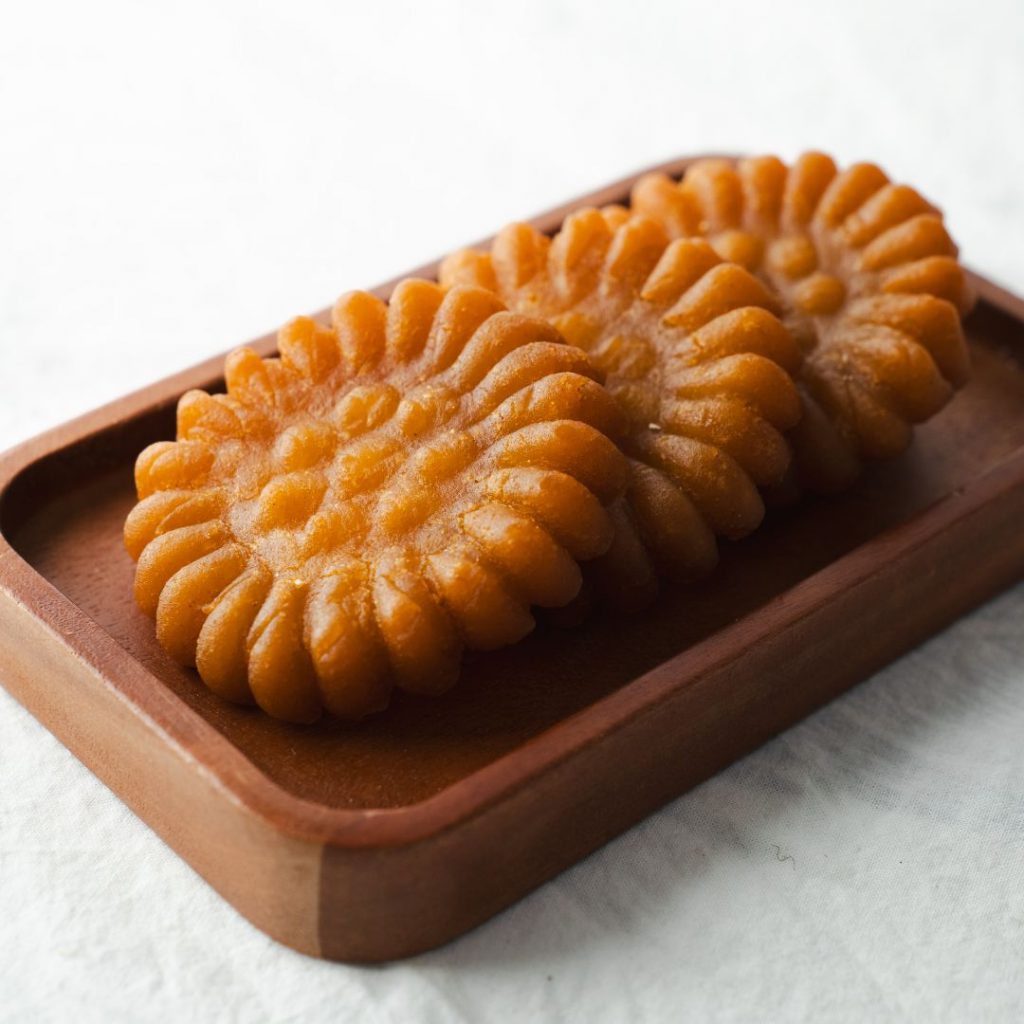 En bild på koreansk yakgwa, gyllene, honungsindränkta kakor med en blommig form och glaserad yta, glänsande och söta