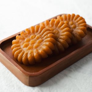 En bild på koreansk yakgwa, gyllene, honungsindränkta kakor med en blommig form och glaserad yta, glänsande och söta