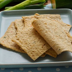 En bild på koreanska fishcakes, gyllenbruna och mjuka fiskkakor i blad som skärs i mindre bitar.