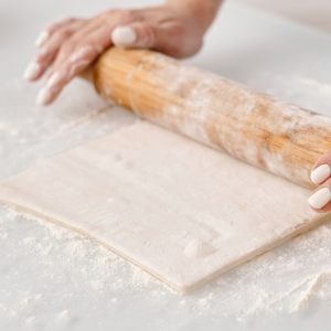 En bit pajdeg, jämn och ljus, redo att fyllas med både söta och salta ingredienser.