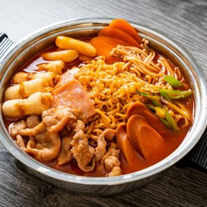 En gryta med budae jjigae, en koreansk gryta med korv, spam, nudlar och röd kryddig buljong