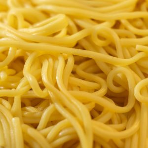 En hög med gyllene gula vetemjölnudlar, långa och släta, perfekta för soppor och wok.