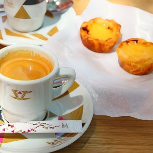 En kopp espresso och en gyllene Pasteis de Nata med krispig smördeg och len vaniljkräm, toppad med en karamelliserad yta. En kopp espresso och en gyllene Pasteis de Nata med krispig smördeg och len vaniljkräm, toppad med en karamelliserad yta.