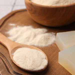 En skål med gelatinpulver, finkornigt och vitt, används för att ge desserter och geléer en fast konsistens.