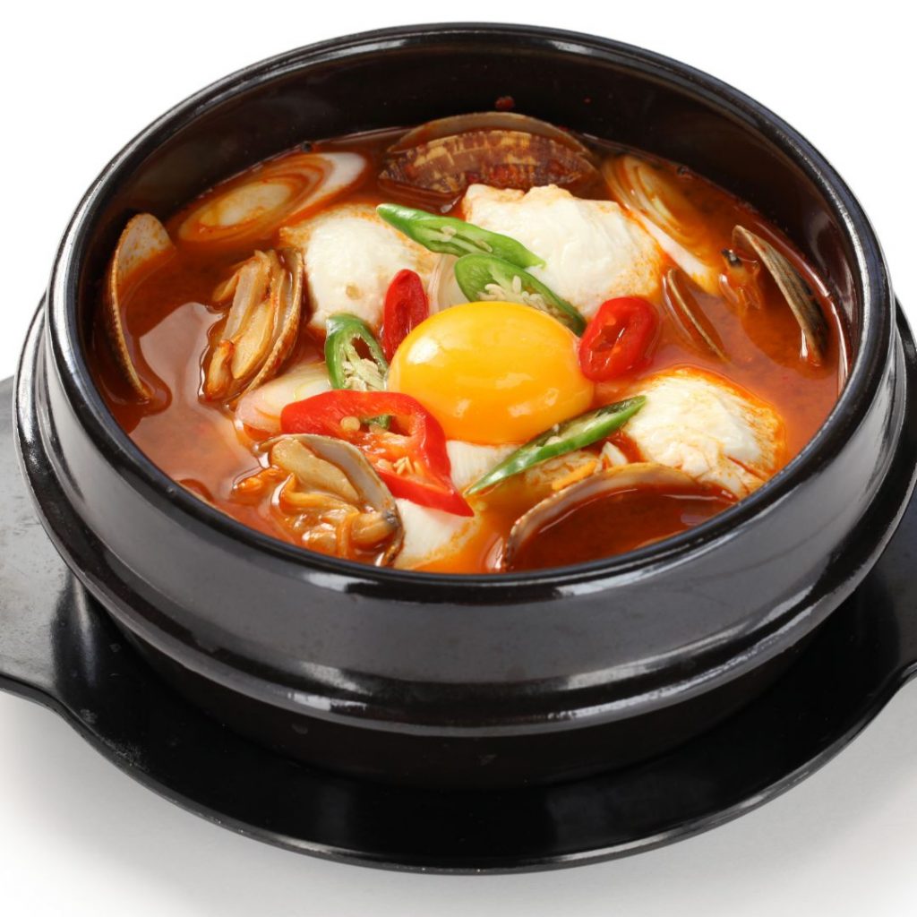 En skål med sundubu jjigae, kryddig tofugryta fylld med silken tofu och grönsaker