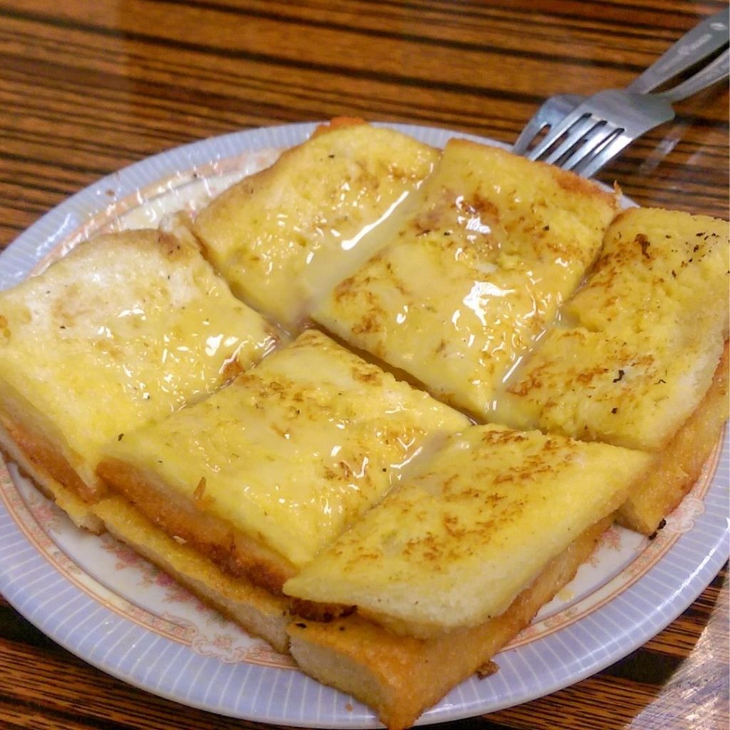 En tallrik med Hong Kong French toast, friterade till gyllenbrun och toppad med smör och sirap