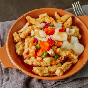 En tallrik med Koreansk tangsuyuk med friterade krispiga fläskkött och sötsur sås.