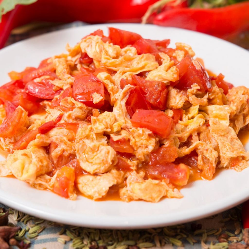 En tallrik med Wokad tomat och äggröra, saftiga tomater och fluffiga ägg i en smakrik sås