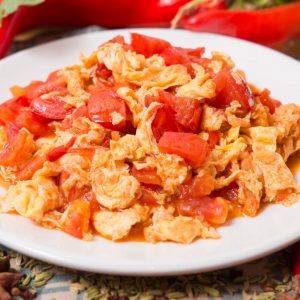 En tallrik med Wokad tomat och äggröra, saftiga tomater och fluffiga ägg i en smakrik sås