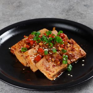 En tallrik med dobu jorim, marinerad tofu i en smakrik sojasås med chiliflakes, garnerad med salladslök