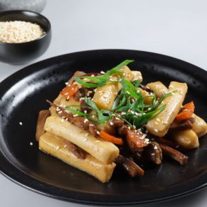 En tallrik med gungjung tteokbokki, stekta riskakor med en söt och sojasmakande sås En tallrik med gungjung tteokbokki, stekta riskakor med en söt och sojasmakande sås