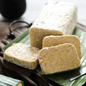 En tallrik med gyllenbruna skivor av tempeh, en fermenterad sojaprodukt med fast konsistens och nötig smak. En tallrik med gyllenbruna skivor av tempeh, en fermenterad sojaprodukt med fast konsistens och nötig smak.