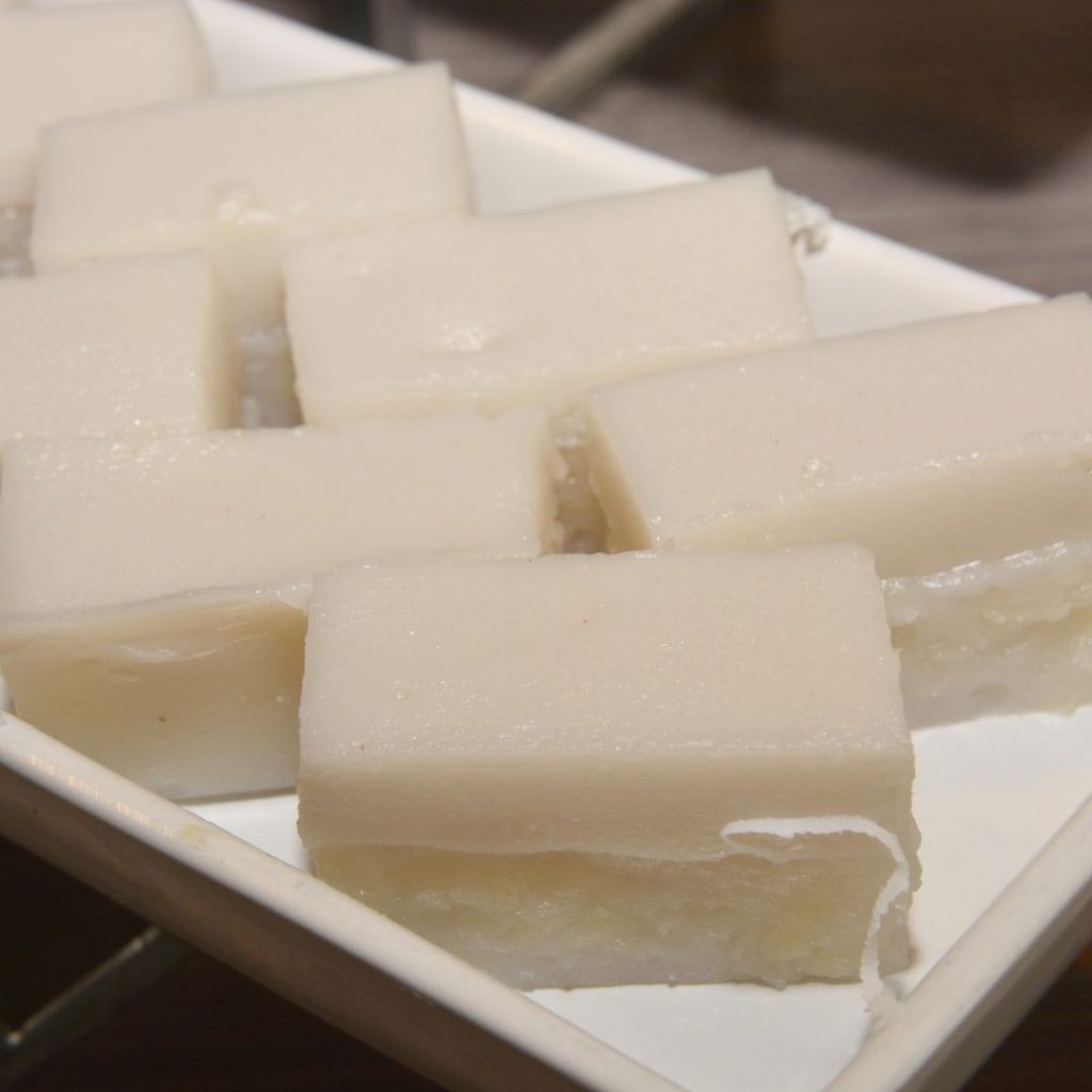 En tallrik med kinesisk coconut jelly, en mjuk, genomskinlig dessert med en lätt kokosarom, skuren i block för servering