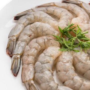 En tallrik med vannamei-räkor, råa, skalade och rosa med en fast konsistens, redo för marinering och tillagning.