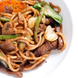 En tallrik med wokade udonnudlar, med kött i strimlor och smaksatt med sojasås och färska grönsaker. En tallrik med wokade udonnudlar, med kött i strimlor och smaksatt med sojasås och färska grönsaker.