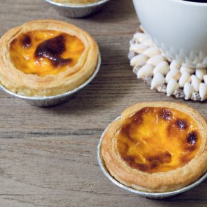 Ett par Macao egg tart, gyllene och krämig med ett sprött smördegsskal och len fyllning.