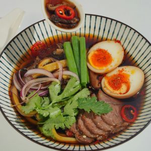 Japansk kryddig biff ramen, fylld med nudlar, kryddstark buljong, saftiga biffskivor och toppad med grönsaker och chili.