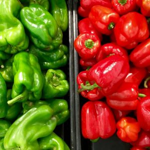 Två högar med röd och grön paprika, krispiga och söta, fylld med C-vitamin och ofta använd i sallader och stekar.