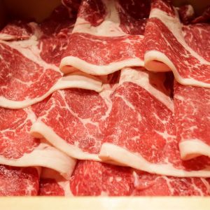 En bambu korg med färska rosaröda feta tunna skivor nötkött redo för shabu-shabu.