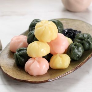 En bild på färgglada Kkultteok, små koreanska riskakor fyllda med sött fyllning som sesam eller röda bönor