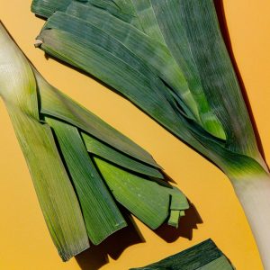 En bild på färsk purjolök med gröna och vita stjälkar, idealisk för att ge smak och textur till soppor, grytor och sallader.