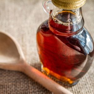 En flaska lönnsirap, i mörk genomskinlig brun, perfekt för pannkakor eller bakverk.
