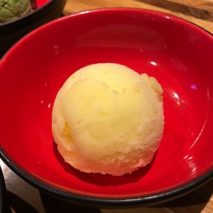 En krämig kula av yuzu glass med en fräsch och citrusaktig smak i en röd japansk skål