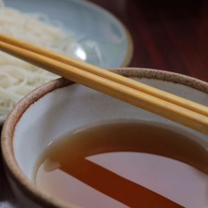 En liten skål med Japansk mentsuyu, en smakrik sås baserad på dashi och soja för nudlar och dip